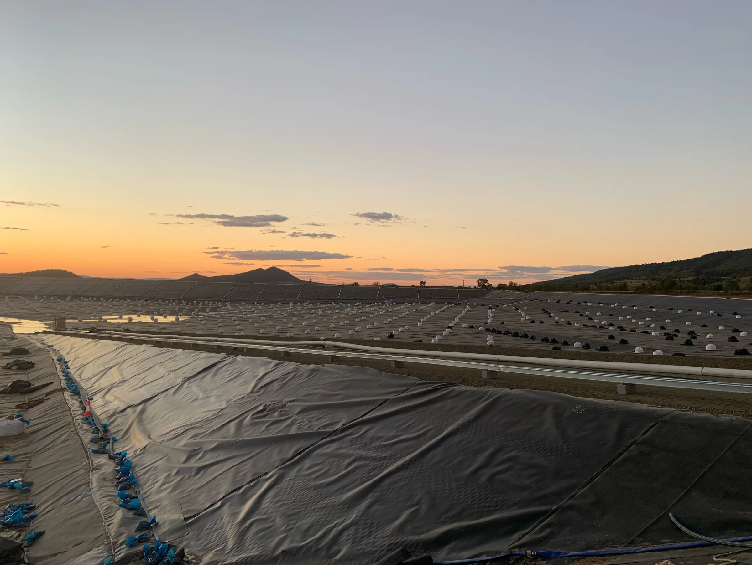 Bituminous geomembrane liner installation at sunset